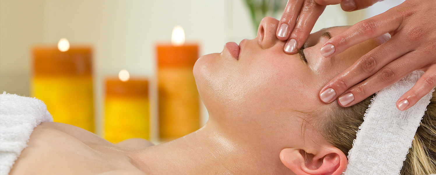 woman getting a facial treatment with candles in the background